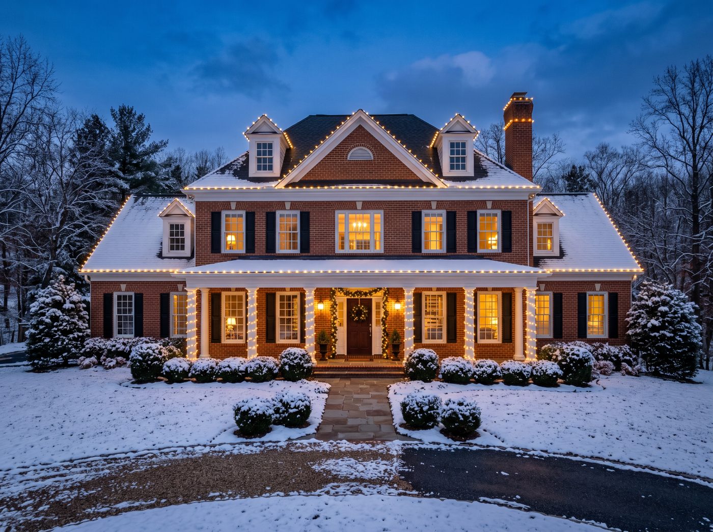 Brick colonial home with professionally hung Christmas lights along the rooflines